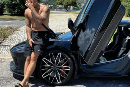 Imagem colorida do rapper Filipe Ret sentado no capô de um McLaren GT - Metrópoles