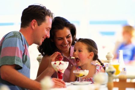 Criança comendo com os pais