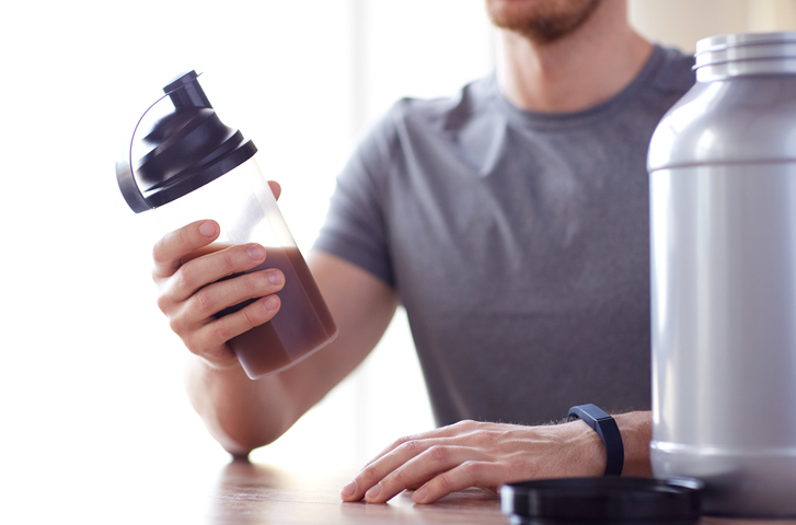 Imagem colorida de homem segurando um recipiente com Whey Protein, suplemento - Metrópoles