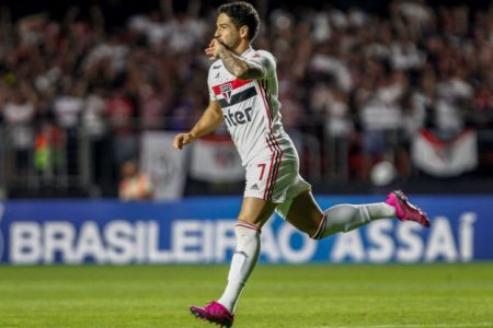 Imagem colorida de homem vestido em uniforme do São Paulo enquanto corre e beija aliança - Metrópoles