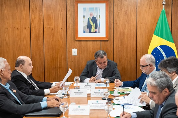 Fotografia colorida de grupo de homens ao redor de mesa de trabalho