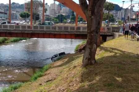 Imagem de um carro parcialmente submergido no rio Paraibuna - Metrópoles