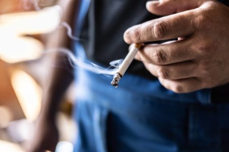 Foto colorida de mão de homem segurando cigarro - Metrópoles