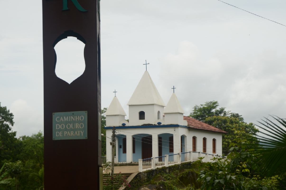 Fotografia colorida de uma igreja em Paraty com a placa simbolizando a estrada real