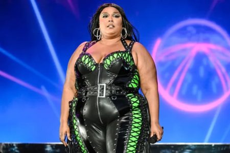 Foto colorida de Lizzo usando macacão preto - Metrópoles