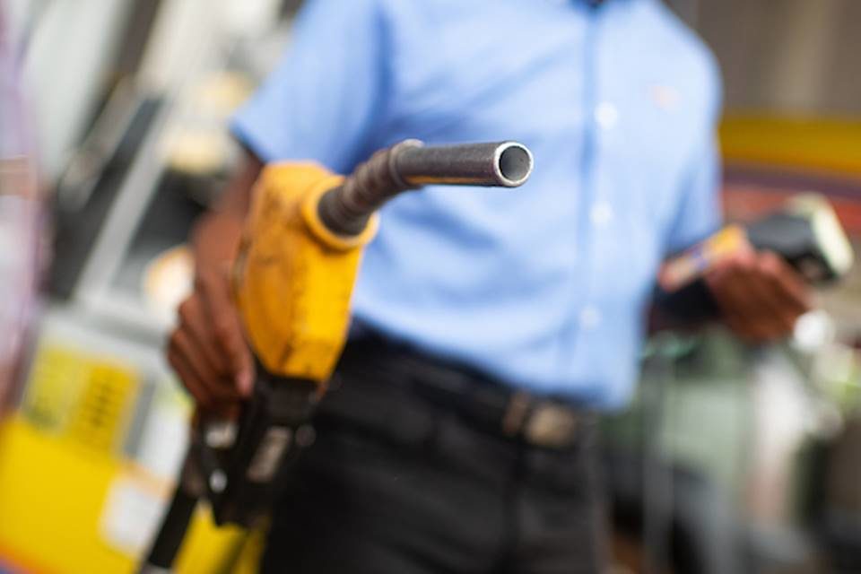 Foto mostra frentista segurando bomba de combustível em posto de gasolina - Metrópoles