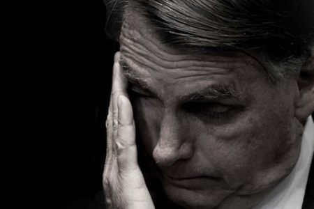 Imagem em preto e branco mostra o ex-presidente Jair Bolsonaro com a mão no rosto - Metrópoles