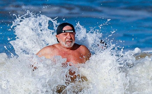 Imagem colorida do presidente Lula tomando banho de mar na Bahia - Metrópoles