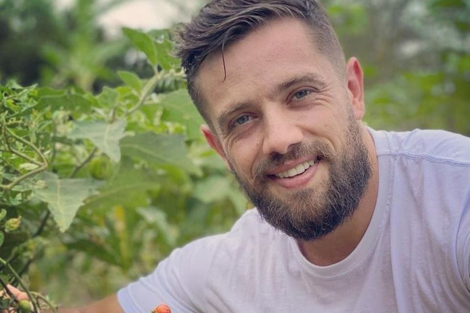 Foto colorida de Rafael Cardoso sorrindo e usando blusa branca - Metrópoles