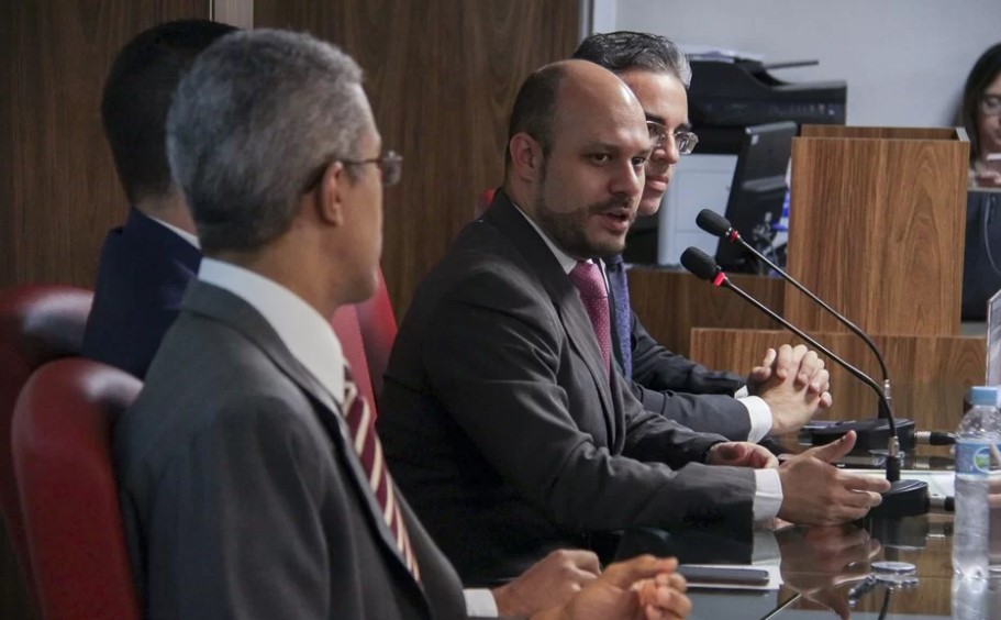 Imagem colorida mostra vários homens de ternos, entre eles, Glauco André Wamburg, presidente interino do INSS - Metrópoles