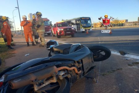 Moto jogada na rua. Bombeiros ao fundo e carros passando