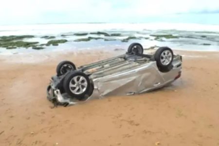 Imagem mostra carro encontrado capotado e parcialmente enterrado em praia da Bahia - Metrópoles