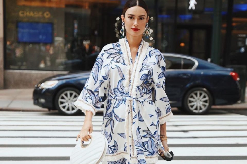 Na imagem com cor, uma mulher branca andando com um conjunto de kimono azul e brnaco - Metrópoles