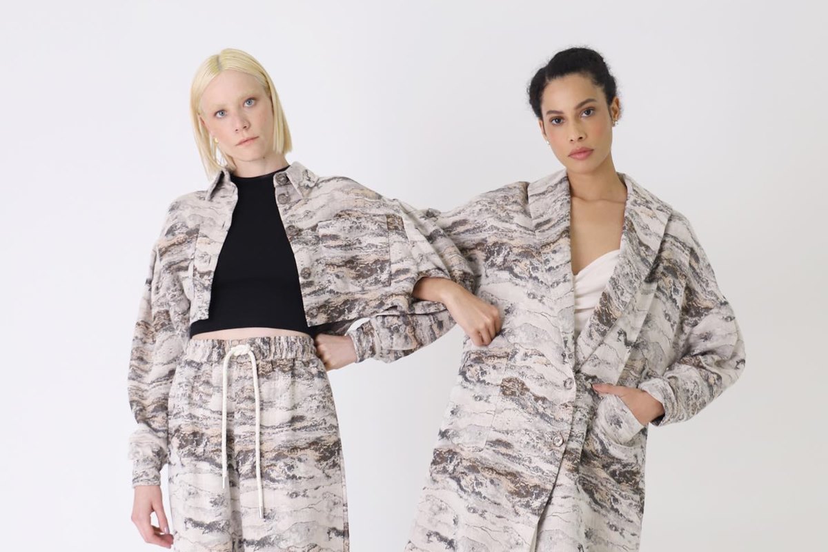 Duas modelos de braços dados usando looks com estampa jacquard em tons de cinza - Metrópoles