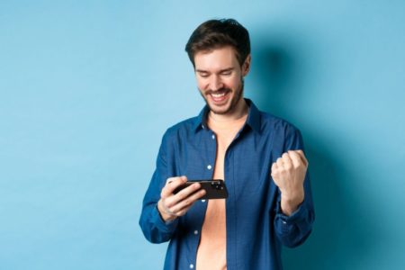 homem torcendo com celular na mão