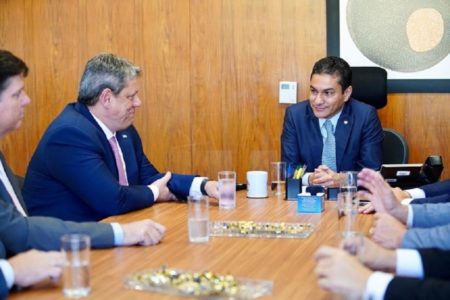 Imagem colorida do presidente do Republicanos Marcos Pereira sentado ao fundo na mesa conversando com o governador Tarcísio de Freitas à esquerda na foto - metrópoles