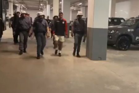 Imagem colocrida do preparador físico peruano que imitou macaco dentro do estádio do Corinthians sendo escoltado por policiais militares - metrópoles