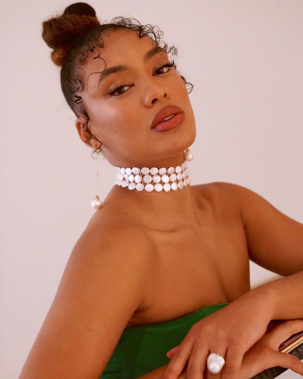 Na imagem com cor, uma mulher negra em uma escada usando um vestido verde - Metrópoles