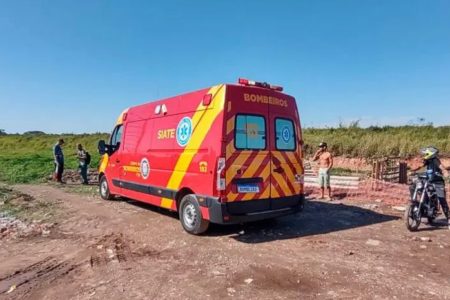 imagem colorida de ambulância vermelha parada em área de terra batida - Metrópoles