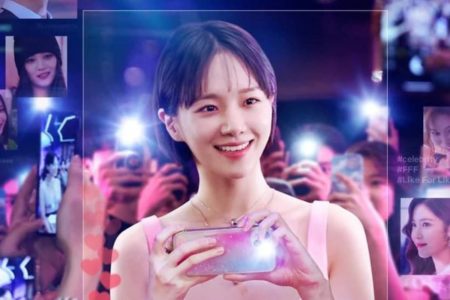 Imagem colorida de Park Gyu Young, protagonista da série Celebrity, da Netflix, segurando um telefone e sorrindo para as câmeras - Metrópoles