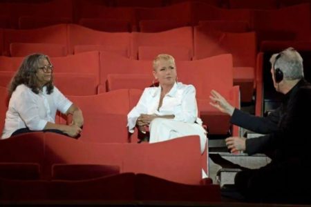 Xuxa sendo entrevistada sentada em uma cadeira vermelha com o reporter - Metrópoles