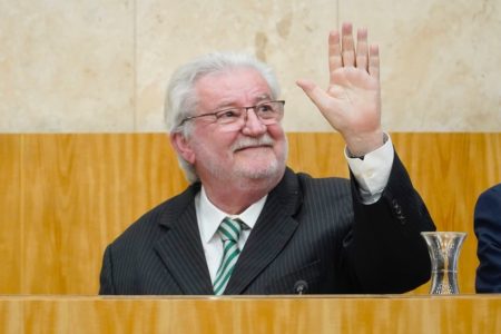 Imagem colorida de Gilberto Natalini. Ele é um homem branco, de barbas e cabelos brancos. Está de terno, sorrindo e acenando com a mão esquerda - Metrópoles