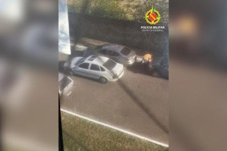 Imagem mostra dois carros, um branco e um prata, estacionados lado a lado em uma rua