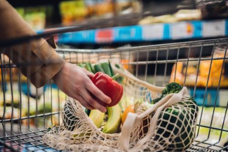 Na foto, uma mão segurando um pimentão vermelho em cima de um carrinho de compras com frutas e verduras - Metrópoles