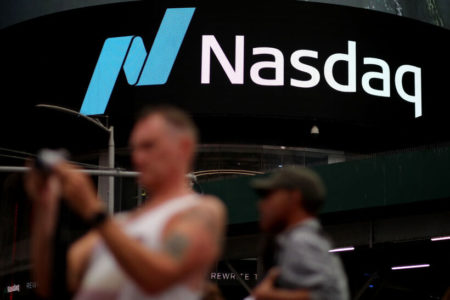 homem segura celular em frente a prédio com o logotipo da Nasdaq - Metrópoles