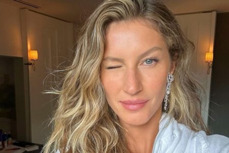 Gisele Bündchen usa uma roupa branca, é loira e olhos claros. Ela está piscando para a foto - Metrópoles