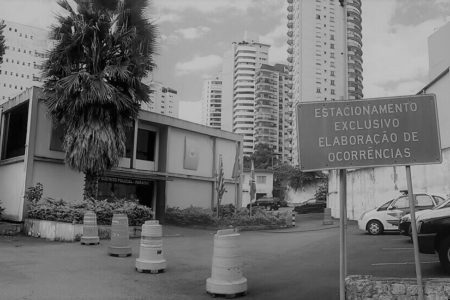 Fotografia em preto e branco da fachada de uma delegacia - Metropoles