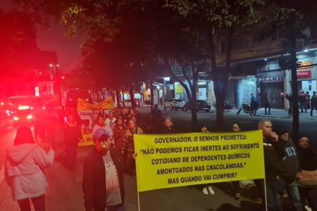 Imagem mostra pessoas caminhando, com faixa amarela nas mãos, em protesto na região central de São Paulo