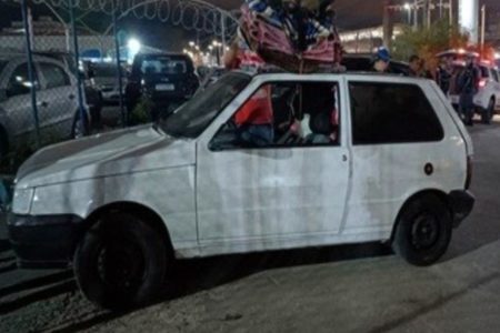 Foto colorida mostra Fiat Uno branco estacionado.