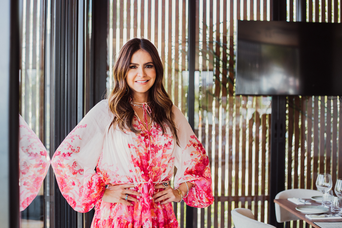 Foto colorida. Mulher branca está posando para a foto com um vestido branco com vermelho - Metrópoles