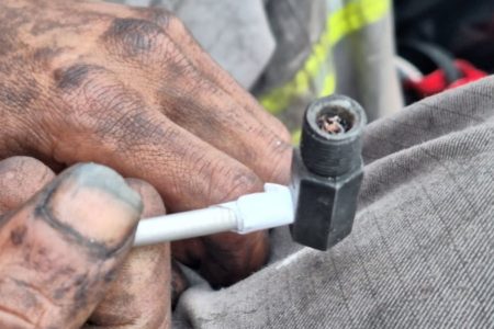 Imagem colorida mostra mão segurando cachimbo de crack com o cabo branco e receptor cinza - Metrópoles