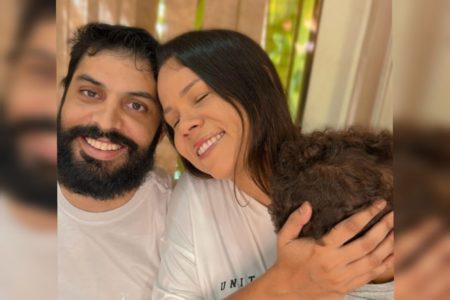 Foto mostra um casal com um homem de barba e uma mulher encostando a cabeça na dele. Ela tem os olhos fechados e uma criança em seus braços - Metrópoles