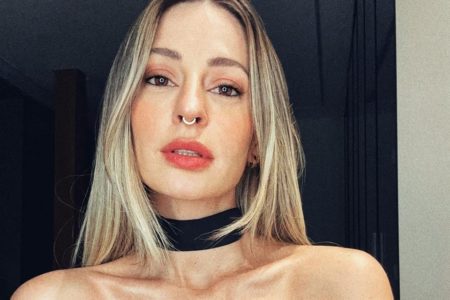 Foto colorida de Tamy Contro. Ela é branca, loira, tem um piercing no nariz e utiliza uma roupa preta - Metrópoles