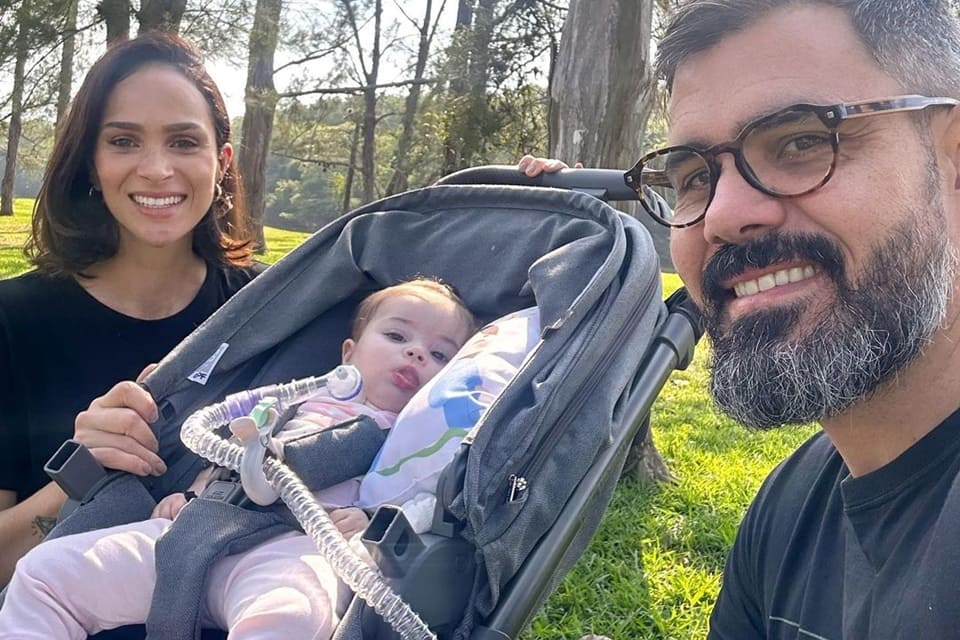 Letícia e Juliano Cazarré posam com a filha caçula, Maria Guilhermina, em um parque - Matrópoles