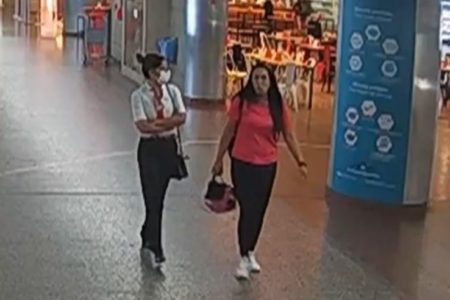 Reprodução colorida de imagems do Aeroporto de Guarulhos com Tamiris Zacharias, funcionária da Gol que usa camisa branca e máscara, e Carolina Pennachiotti, da empresa WFS Orbital, de vermelho, no saguão do aeroporto de Guaruhlos - metrópoles