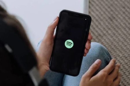 Foto colorida de uma pessoa segurando o celular com o app Spotify - Metrópoles