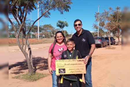 uma mulher, um homem e uma criança segurando um cheque