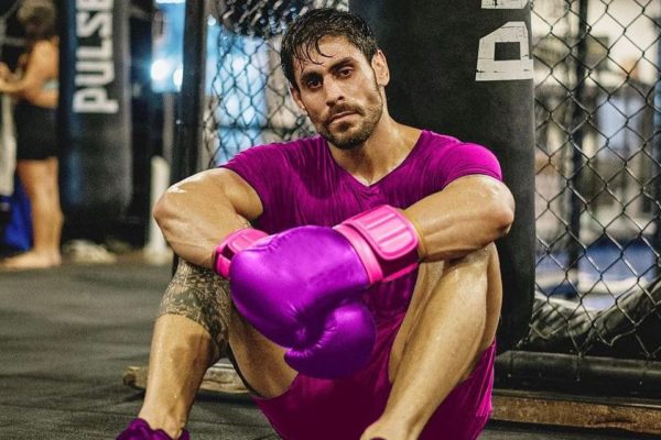Cara de Sapato está de camisa, shorts e luva de boxe roxa. Ele é branco e tem o cabelo escuro - Metrópoles