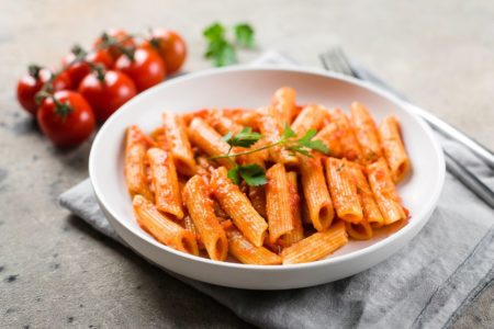 Macarrão em um prato de fundo branco com tomates - Metrópoles