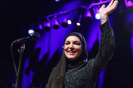 Foto colorida de Sinéad O'Connor sorrindo em show - Metrópoles