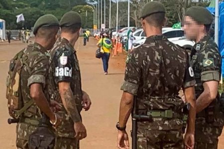 Soldados em frente a quartel do Exército observam pessoa de verde e amarelo