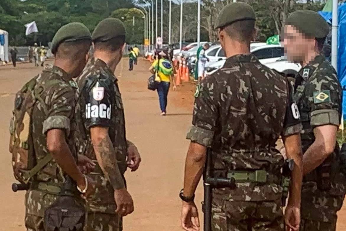 Soldados em frente a quartel do Exército observam pessoa de verde e amarelo