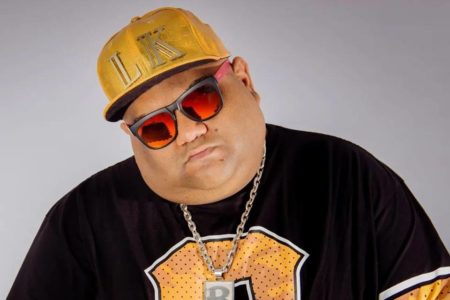 Foto colorida de DJ Baphafinha usando boné, cordão e blusa preta - Metrópoles