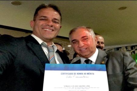 Homem ao lado do senador Izalci segurando diploma