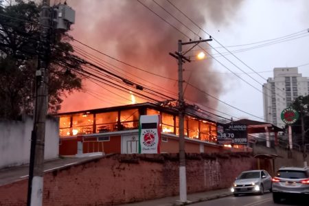 Estrutura de pizzaria com fogo em seu interior, exalando fumaça cinza - Metrópoles