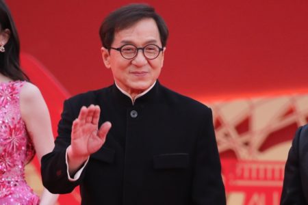 Foto colorida de Jackie Chan. O ator é branco, tem o cabelo preto, usa óculos de grau e está usando uma roupa toda preta - Metrópoles